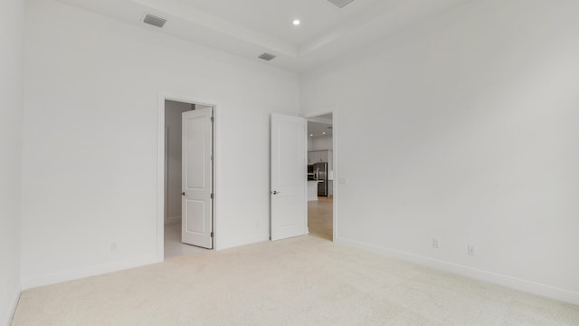 unfurnished bedroom featuring light carpet and stainless steel refrigerator