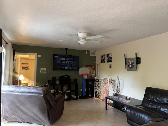 living area with ceiling fan, a textured ceiling, and light tile patterned floors