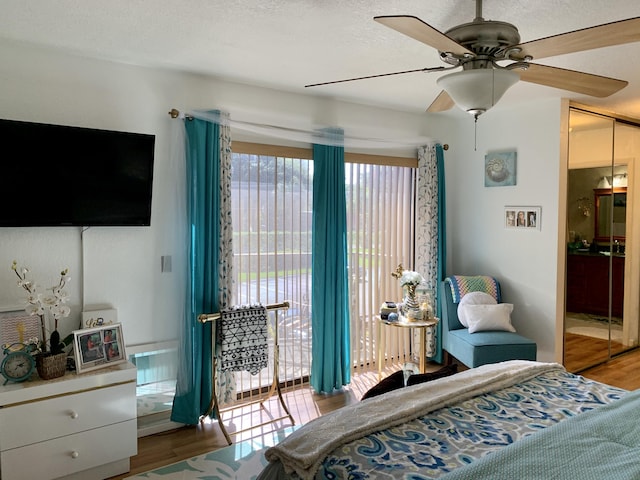 bedroom with access to outside, wood finished floors, and a ceiling fan