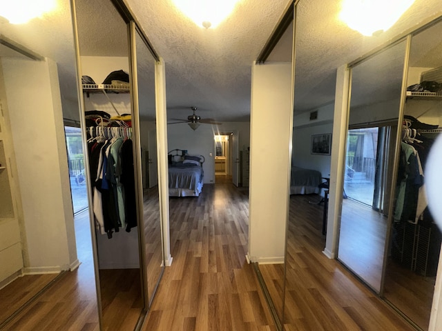 hallway with wood finished floors, a textured ceiling, and baseboards