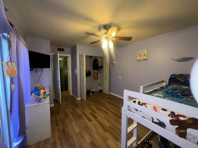 bedroom with wood finished floors, baseboards, a ceiling fan, a textured ceiling, and a closet