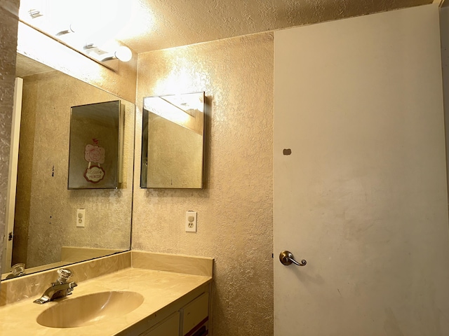 bathroom featuring a textured wall, vanity, and a textured ceiling
