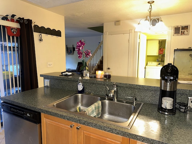 kitchen featuring washer / dryer, stainless steel dishwasher, a sink, dark countertops, and hanging light fixtures