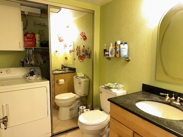 bathroom featuring washer / clothes dryer, toilet, a textured wall, tile patterned flooring, and vanity