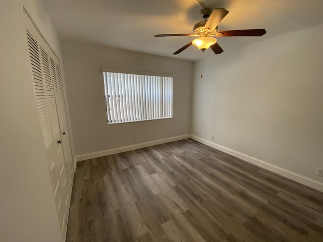 unfurnished bedroom featuring ceiling fan, a closet, and dark wood-type flooring