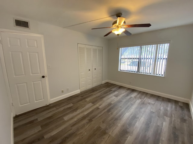 unfurnished bedroom featuring a closet, ceiling fan, and dark hardwood / wood-style flooring