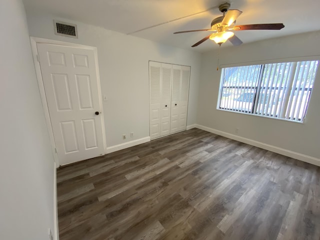 unfurnished bedroom with ceiling fan, dark hardwood / wood-style floors, and a closet