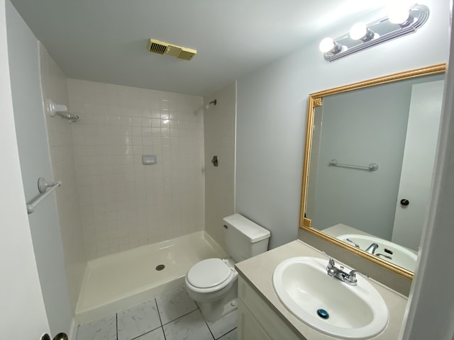 bathroom featuring tiled shower, vanity, and toilet