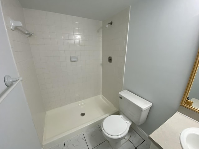 bathroom featuring toilet, a tile shower, and vanity