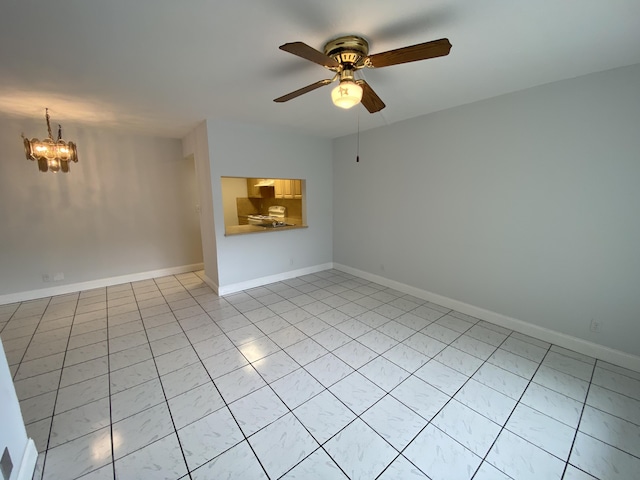 spare room featuring ceiling fan with notable chandelier