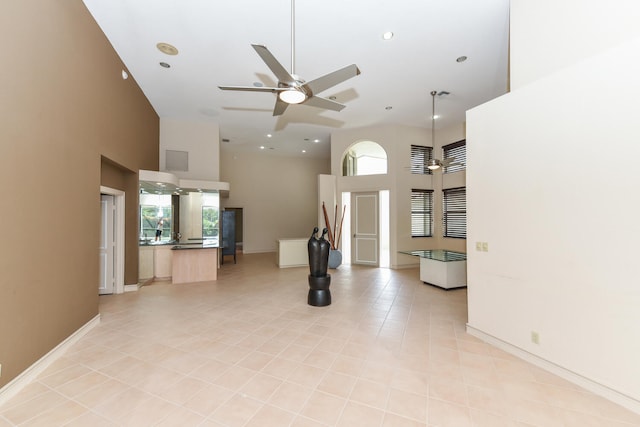 unfurnished living room with a towering ceiling, light tile patterned floors, and a healthy amount of sunlight