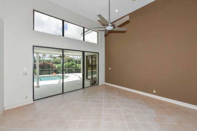 tiled spare room with ceiling fan and a high ceiling