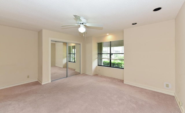 unfurnished bedroom with ceiling fan, light carpet, and a closet