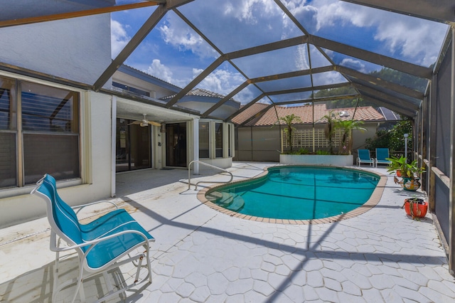 view of swimming pool featuring glass enclosure, ceiling fan, a patio area, and a water slide