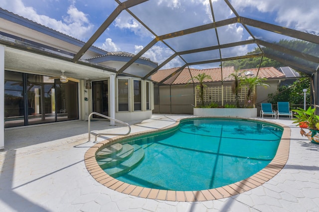 view of pool featuring a patio, glass enclosure, and ceiling fan