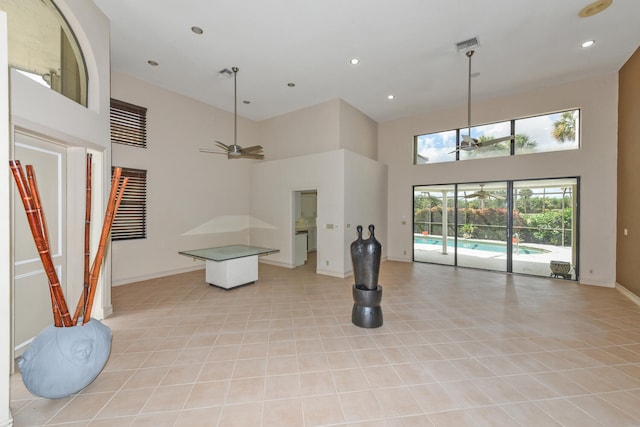 living room with a high ceiling, ceiling fan, and light tile patterned flooring