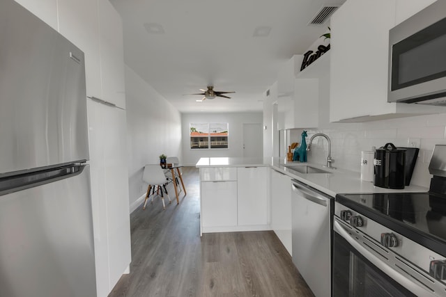 kitchen with sink, tasteful backsplash, appliances with stainless steel finishes, kitchen peninsula, and white cabinets