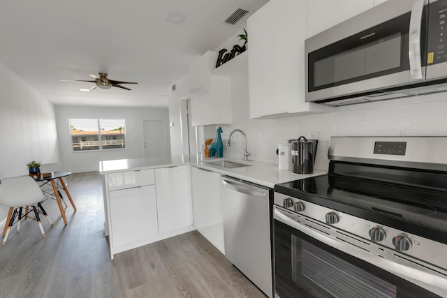 kitchen featuring sink, white cabinetry, tasteful backsplash, appliances with stainless steel finishes, and kitchen peninsula