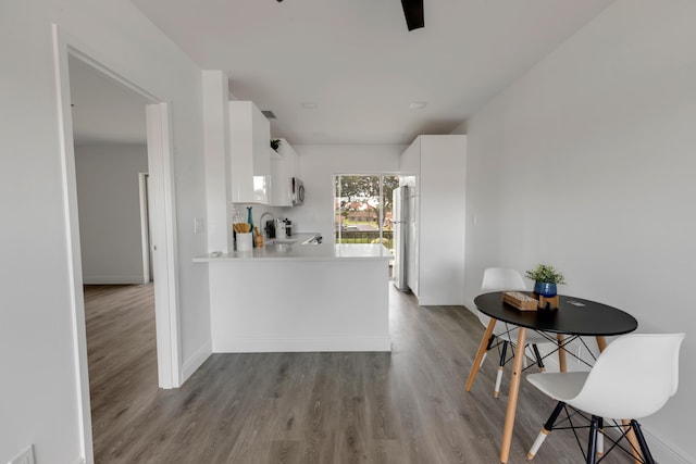 kitchen featuring refrigerator, kitchen peninsula, white cabinets, and light wood-type flooring