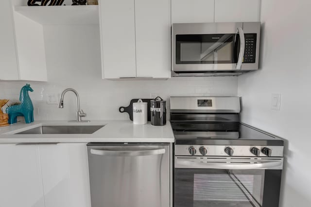 kitchen with stainless steel appliances, sink, white cabinets, and decorative backsplash