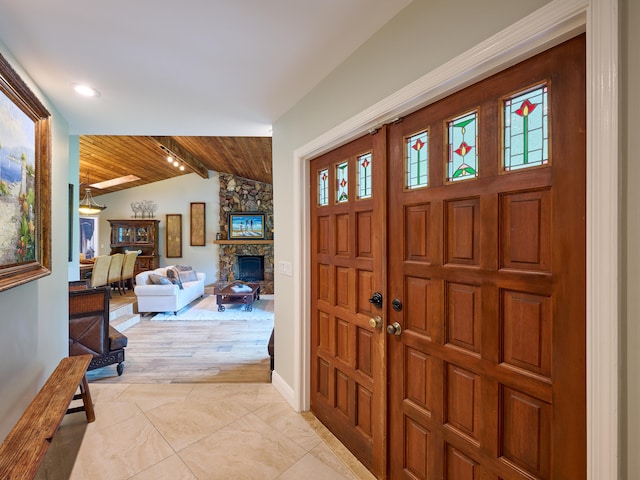 foyer entrance featuring lofted ceiling, a healthy amount of sunlight, wood ceiling, and a fireplace