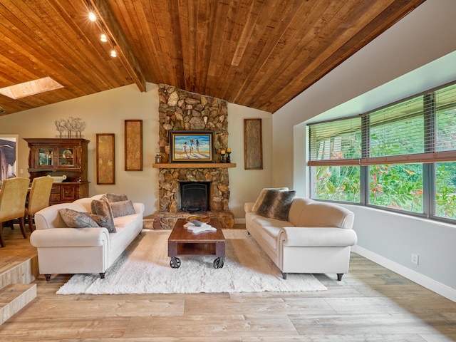 living room with a stone fireplace, vaulted ceiling with skylight, light wood-type flooring, and wooden ceiling