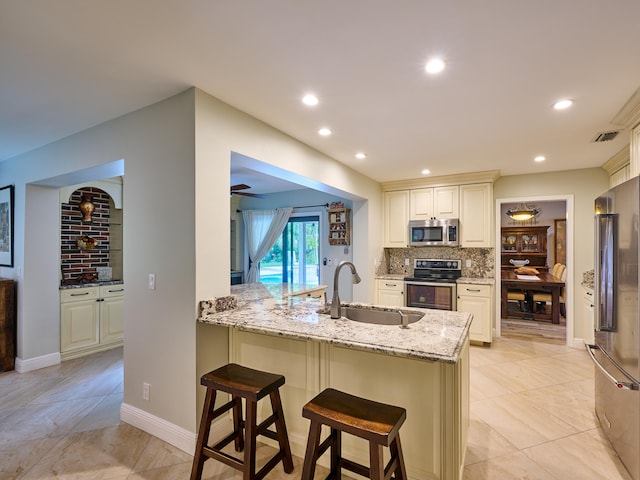 kitchen with tasteful backsplash, stainless steel appliances, light stone counters, light tile patterned flooring, and ceiling fan