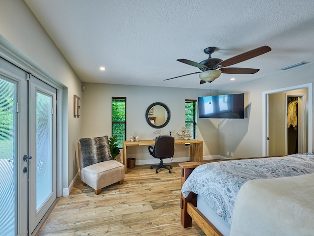 bedroom with ceiling fan, french doors, light hardwood / wood-style floors, a textured ceiling, and access to exterior