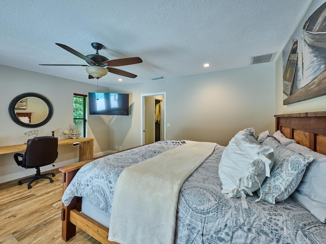 bedroom featuring a textured ceiling, wood-type flooring, and ceiling fan