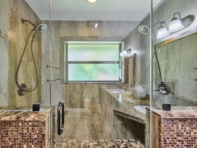 bathroom with dual vanity, tiled shower, and tile walls