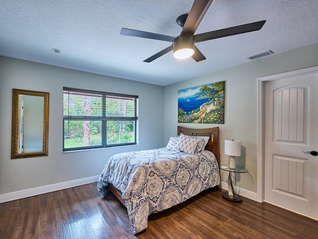 bedroom featuring ceiling fan, a textured ceiling, and dark hardwood / wood-style flooring