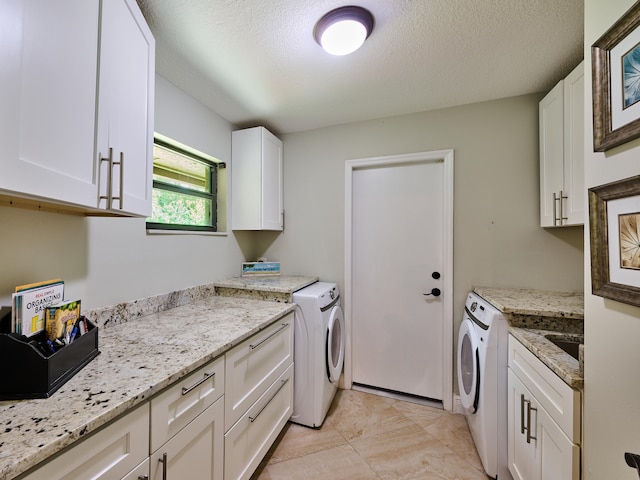 clothes washing area featuring cabinets, washer and clothes dryer, light tile patterned floors, and a textured ceiling