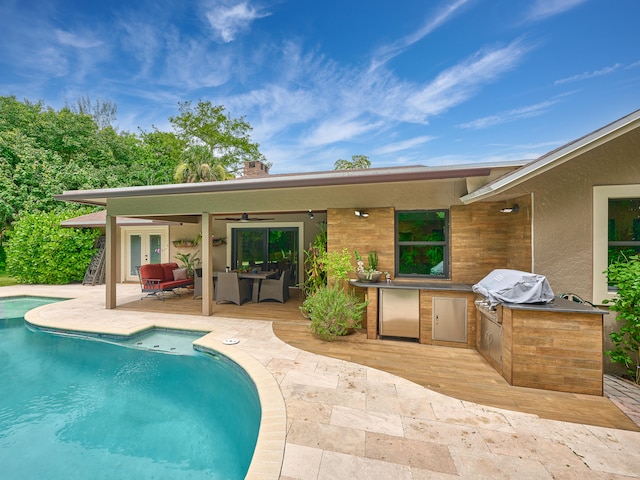 view of pool with exterior kitchen, a patio, an outdoor living space, and grilling area