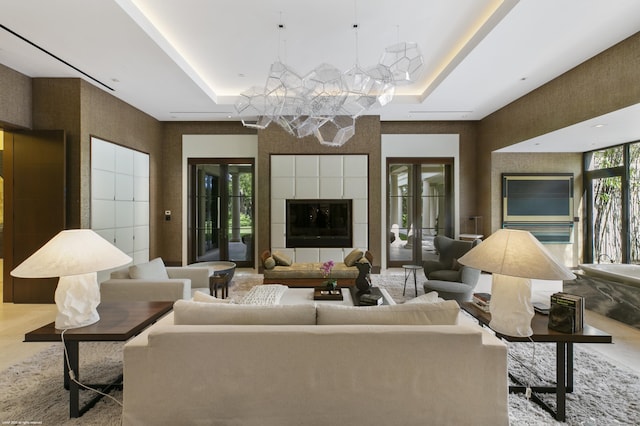 living room with a tray ceiling and a tiled fireplace