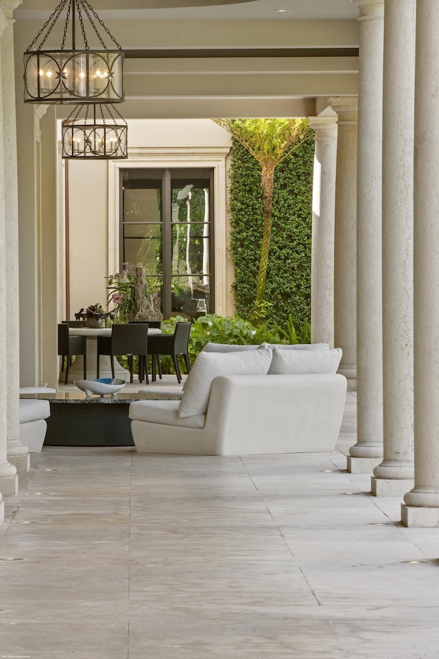 exterior space featuring ornate columns and an inviting chandelier