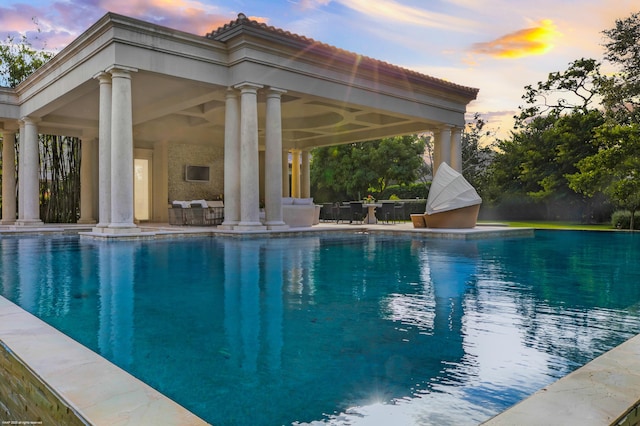 pool at dusk featuring a gazebo and a patio