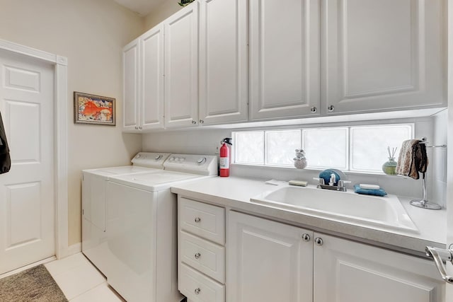 clothes washing area with cabinets, light tile patterned floors, sink, and washing machine and dryer