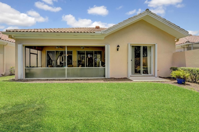 back of house with ceiling fan and a lawn