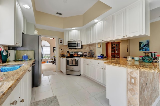 kitchen featuring light stone counters, light tile patterned floors, white cabinetry, and appliances with stainless steel finishes