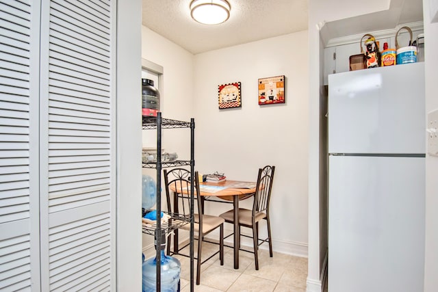 dining space with a textured ceiling and light tile patterned floors