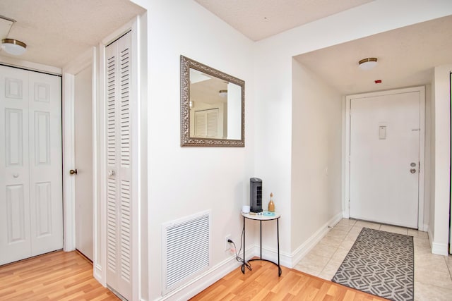 foyer entrance with light hardwood / wood-style flooring and a textured ceiling