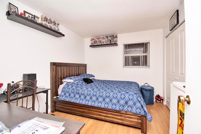 bedroom with light hardwood / wood-style flooring, a closet, and a textured ceiling