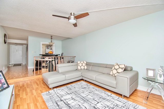 living room with a textured ceiling, light hardwood / wood-style flooring, and ceiling fan