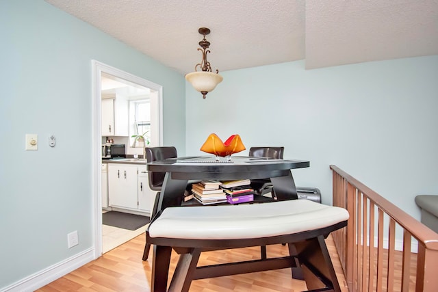 dining space with light hardwood / wood-style floors, sink, and a textured ceiling