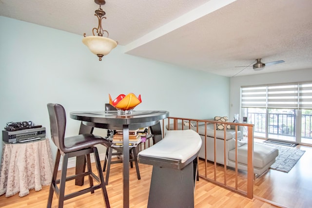 dining space with a textured ceiling, ceiling fan, and light wood-type flooring