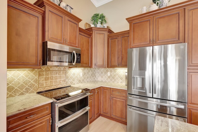 kitchen with backsplash, light stone countertops, stainless steel appliances, and ornamental molding