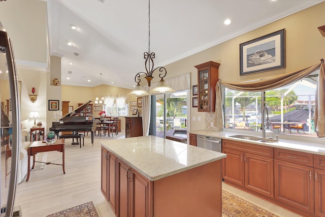 kitchen featuring light stone countertops, sink, hanging light fixtures, stainless steel dishwasher, and a kitchen island