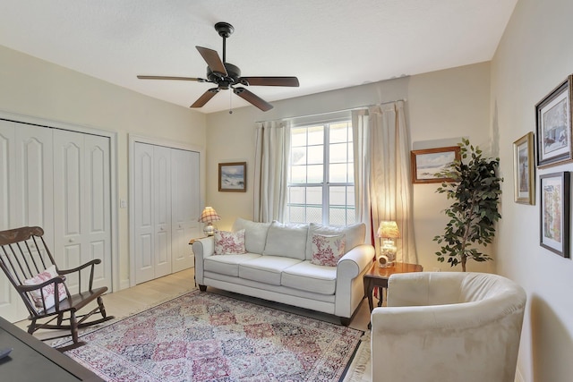 living area with ceiling fan, a textured ceiling, and light hardwood / wood-style flooring