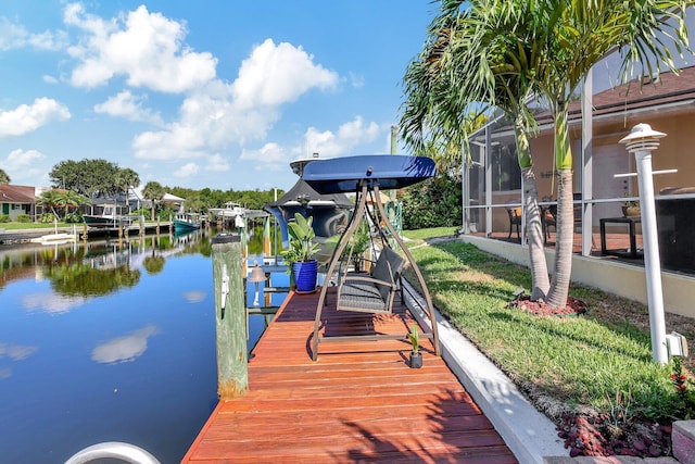 view of dock featuring a lanai, a water view, and a yard