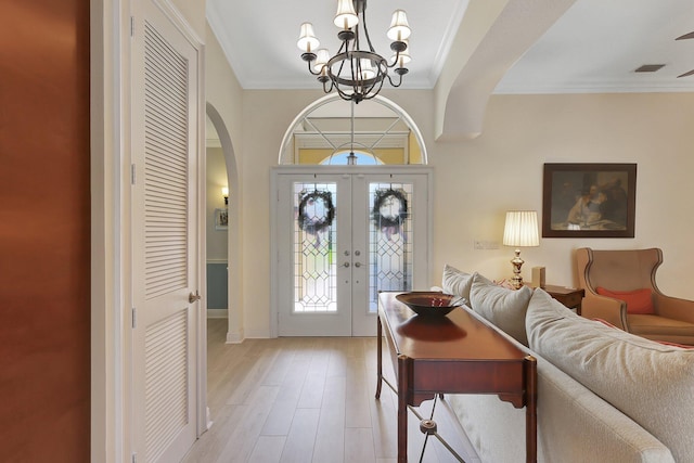 foyer entrance with a chandelier, french doors, light hardwood / wood-style floors, and ornamental molding